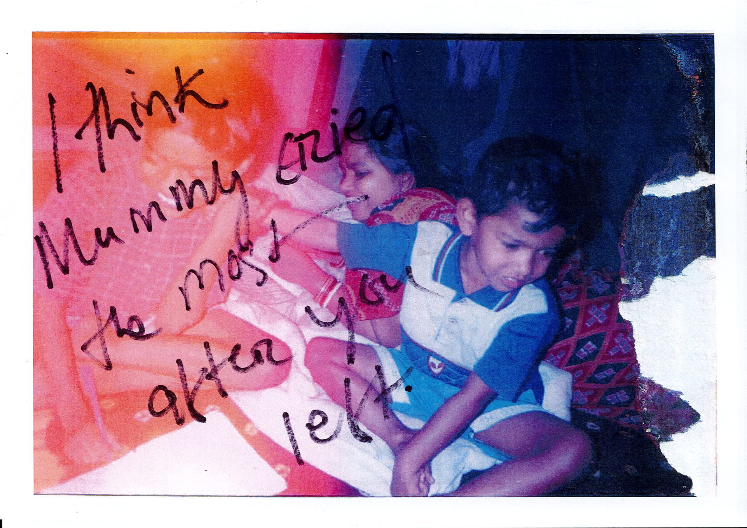 An old family photo with handwritten text on it. A kid with his brother and mother are on the bed.